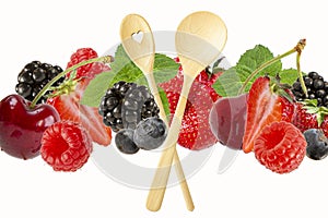 Assorted berries and wooden spoons isolated on white background.Cherries,blueberries,raspberries,mulberries and mint leaves in a