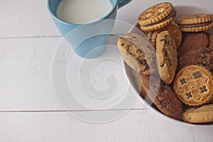 Assorted biscuits in bowl with cup milk