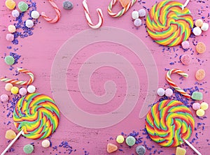 Assorted candy and lollipop on pink wood table.