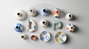 Of assorted ceramic vases and bowls is arranged on a light gray