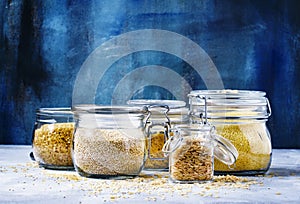 Assorted cereals in glass jars: kinoa, bulgur, couscous, orzo, b