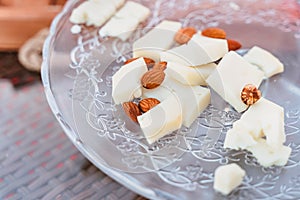 Assorted cheese on a glass dish with nuts, almonds and hazelnuts