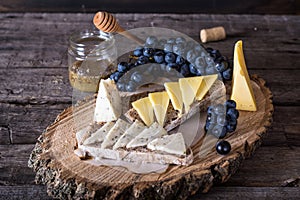 Assorted cheeses with grapes, bread, honey. Goat cheese. wooden board. Italian appetizer. bruschetta. Breakfast concept