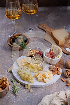 Assorted cheeses on marble plate with figs, nuts, grapes and honey