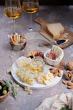 Assorted cheeses on marble plate with figs, nuts, grapes and honey
