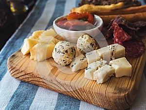 Assorted cheeses and sausages on a wooden board on a table