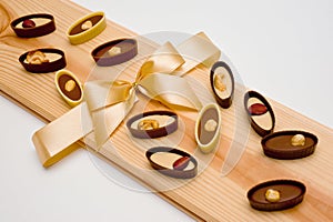 Assorted chocolate candies with peanuts, cashews, hazelnuts and almond nuts, shot on wooden background