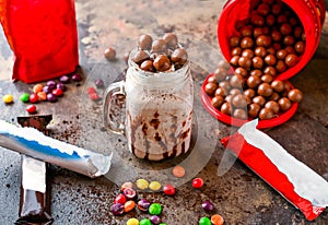 Assorted chocolate Milkshake with ice cream, colorful bunty candy and whipped cream served in jar isolated on dark background side