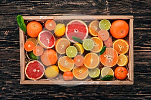 Assorted citrus fruit in a wooden box. Orange, tangerine, grapefruit, lemon. On a wooden background.