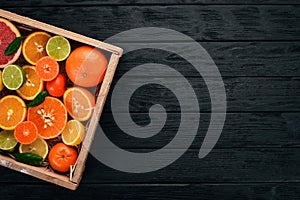 Assorted citrus fruit in a wooden box. Orange, tangerine, grapefruit, lemon. On a wooden background.