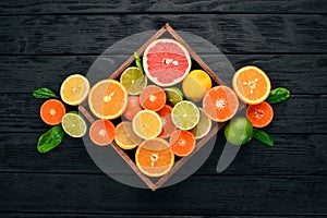 Assorted citrus fruit in a wooden box. Orange, tangerine, grapefruit, lemon. On a wooden background.