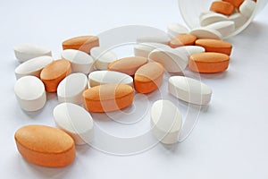 Assorted colorful pharmaceutical medicine pills, tablets and capsules with bottle on white background