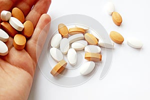 Assorted colorful pharmaceutical medicine pills, tablets and capsules in hand on white background