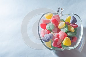 Assorted colorful sweets in a trasparente bowl, light blue background, children's concept and joy photo