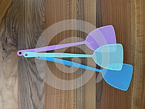 Assorted coloured fly swatters against a wooden background