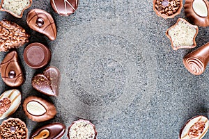 Assorted delicious chocolate pralines background on grey texture, place for text, product photography for patisserie