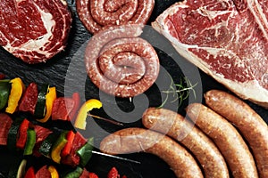 Assorted delicious raw meat with vegetable on a barbecue with t-bone steak, sausages and meat Skewers