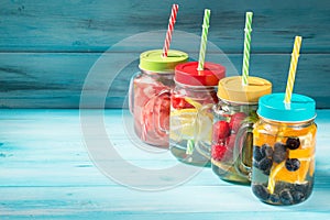 Assorted detox water cocktails in glass jars on wooden background