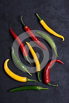 Assorted different colored chili peppers on dark background