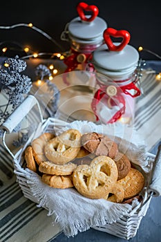 Assorted different types of homemade cookies in white wicker basket on dark background