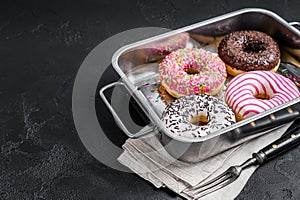 Assorted donuts with chocolate, pink glazed and sprinkles Doughnut. Black background. Top view. Copy space