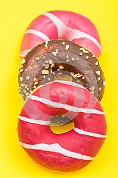 Assorted donuts with chocolate on yellow background
