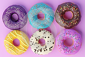 Assorted donuts with colorful icings on pink background.