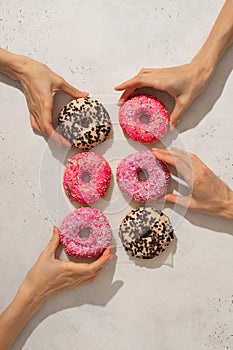 Assorted donuts with some woman hands taking on white background