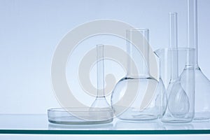 Assorted empty laboratory glassware, test-tubes. Blue tone medical background. Copy space