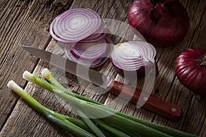 Assorted farm fresh onions on a wooden table with spring onions
