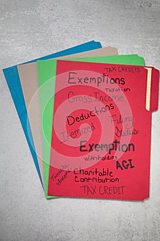 Assorted file folders different colors tax credit exemptions taxation gross income handwritten on red folder