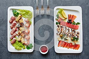 Assorted fish, red fish canapes, eggplant and ham rolls stuffed with cheese and herbs on a white plate on a gray background