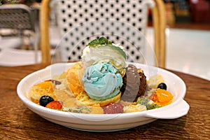 Assorted flavors scoop ice cream with giwi, strawberry, orange, blueberry, banana fruit and topping dress whip cream.