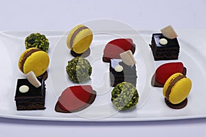 Assorted french pastries in a platter as petit four with macaroons, chocolate cake, pistachio balls