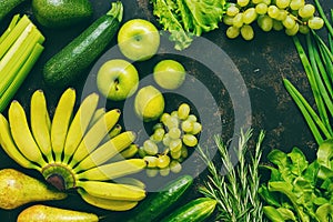 Assorted fresh green and yellow fruits and vegetables on a dark background, top view, copy space. assorted vegetables. The concept