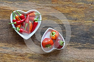 Assorted fresh hot peppers long and round pods on white plates top view