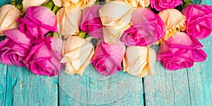 Assorted fresh multicolored roses on turquoise wooden background