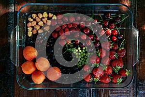 Assorted fresh seasonal fruits and berries: strawberries, apricots, cherries, mulberry, raspberries washing under