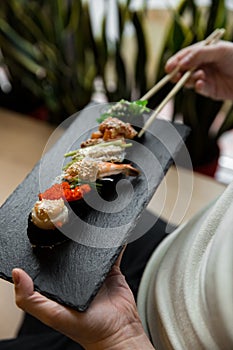 Assorted fresh sushi gunkan maki with seafood. set of gunkans in hands. Selective focus.