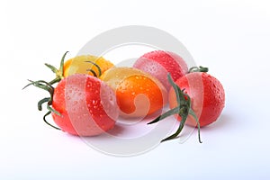 Assorted fresh tomatoes with green leaves isolated on white background