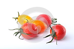Assorted fresh tomatoes with green leaves on white background