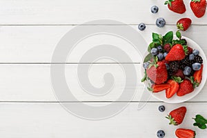 Mixed berries in glass bowls on white wooden table top view