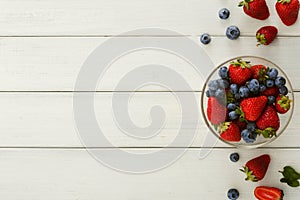 Mixed berries in glass bowls on white wooden table top view