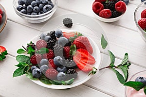 Mixed berries in glass bowls on white wooden table