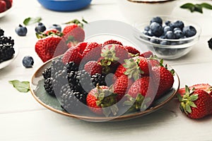 Mixed berries in glass bowls on white wooden table