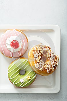 Assorted glazed fried donuts on a plate