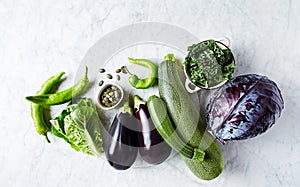 Assorted green and purple organic vegetables on marble background