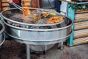Assorted grilled meat on barbecue grill with smoke and flames of fire in the background.