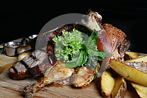 Assorted grilled meat. Knuckle, steaks, chicken duck, potatoes on a wooden board.