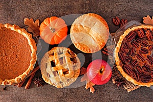 Assorted homemade autumn pies. Top view table scene over dark stone.
